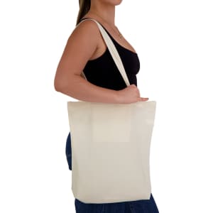 A person holding a cream-coloured tote bag, featuring long straps and a minimalist design.