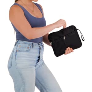 A black utility pouch with a zippered compartment and a wrist strap, held in a woman's hand.
