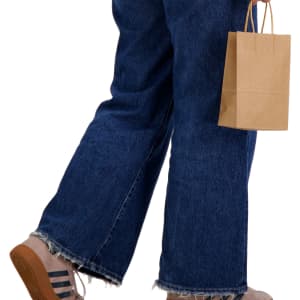 A small brown paper bag held in a hand, paired with wide-leg denim jeans and a casual footwear style.
