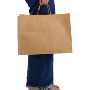 A large brown paper bag with handles, held by a person wearing jeans and shoes. It features a simple design.