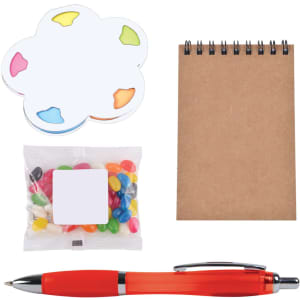 A colorful sticky note pad, a bag of jelly beans, a notepad, and a red pen arranged on a white background.