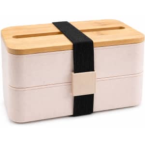 A pink eco lunch box with a bamboo lid and black strap, featuring two compartments and a branding logo.