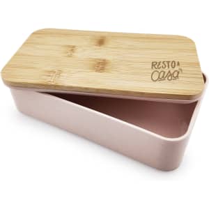 A pink lunch box with a bamboo lid and an engraved logo, featuring a divided interior.