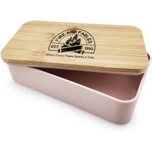 A pink lunch box with a bamboo lid and a logo on top, featuring a two-compartment design.