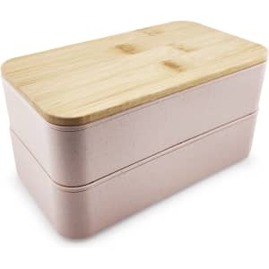 A pink two-tier lunch box with a bamboo lid and a smooth finish, featuring a logo on the side.