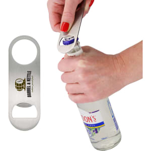 A drink bottle opener in stainless steel, with a round hole and a logo, being used to open a bottle.