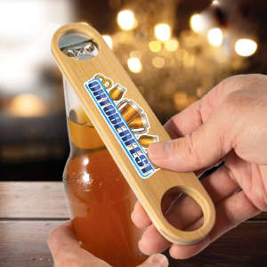 A drink bottle opener made of bamboo, featuring a logo, held over a bottle against a blurred background.