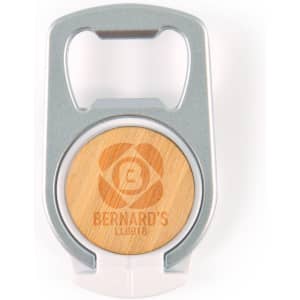 A drink bottle opener phone stand in silver and wood, featuring a circular design with a logo.