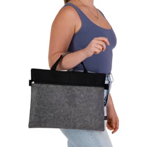 A grey felt satchel with black accents, held by a person wearing a blue top and light jeans. It has a logo.