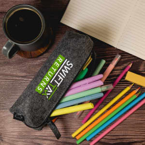 A grey felt utility case filled with colourful pens and markers, alongside a cup of coffee and a notebook.