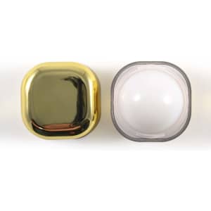 A square cosmetic container with a shiny gold lid and a transparent base, featuring a logo.