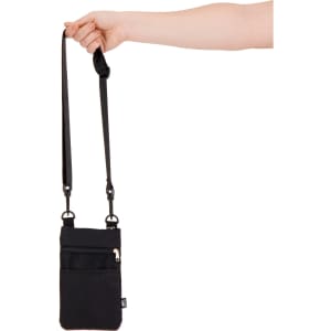 A black Wallaby Neck Pouch with a strap is being held by a hand, featuring a front zip pocket and branding.