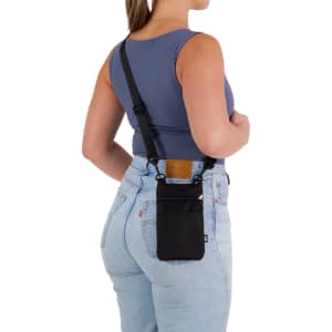 A black neck pouch is worn on a woman's back, featuring a strap and a logo. The woman is in fitted jeans and a tank top.