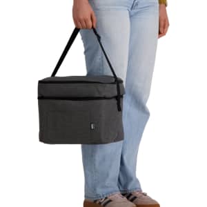 A grey cooler bag with a handle, held by a person wearing light blue jeans and casual shoes.