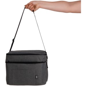 A hand holds a grey cooler bag with a strap, featuring a front pocket and zipper closure. It has a logo.