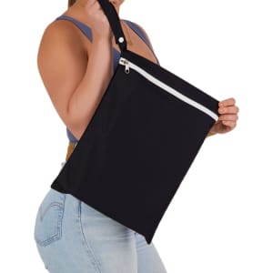 A person holding a black Cosi Wet Bag with a white zip and shoulder strap. The bag appears spacious and lightweight.