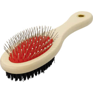 A pet grooming brush with a cream handle, red bristle pad, and black bristles on the opposite side. Features a logo.
