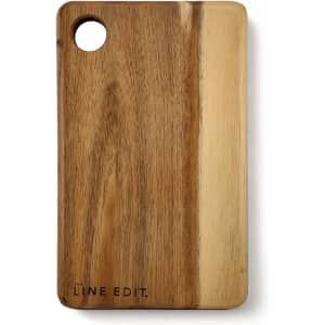 An acacia serving board in warm brown tones, featuring a circular cut-out and a logo on the side.