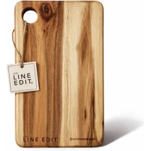 Acacia serving board with a natural wood finish, featuring a hole for hanging and a tag with branding.