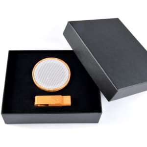 A sleek gift box containing a bamboo wireless speaker and a matching bamboo phone stand.