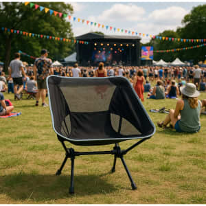 A black folding chair with a mesh backrest set against a vibrant outdoor festival scene.