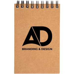 A spiral-bound pocket notebook with a kraft cover featuring the logo "AD" along with the text "BRANDING & DESIGN".