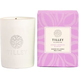 A white scented soy candle is accompanied by a purple box, labelled "Sweet Berries & Musk", featuring a logo.