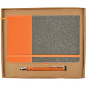 An orange and gray notebook with an elastic band and a matching orange pen inside a cardboard gift box.
