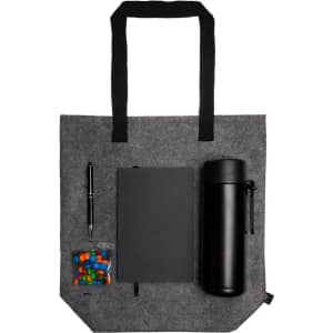 A gray tote bag contains a black drink bottle, a black notebook, a pen, and a bag of colorful candies.