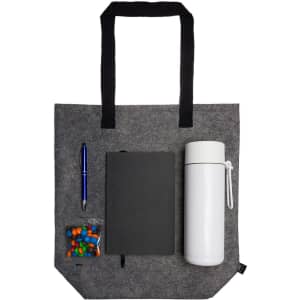 A gray tote bag with a white drink bottle, a black notebook, a pen, and a small container of colorful candies.