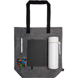 A gray tote bag containing a drink bottle, a notebook, a pen, and a small bag of candies.