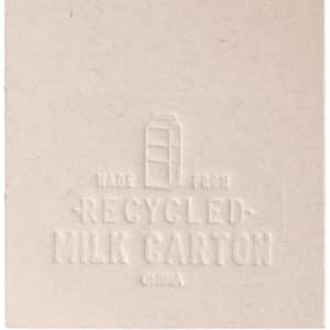 A beige bookmark shaped like a milk carton, made from recycled materials, featuring an embossed design and a logo.