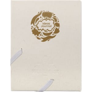 A cream-coloured journal with a decorative gold design and an elastic band closure. It features a logo on the cover.