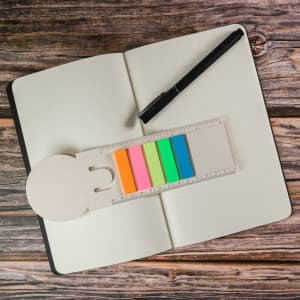 A milk carton-shaped bookmark in light beige with colorful post-it flags in pink, orange, yellow, green, and blue.