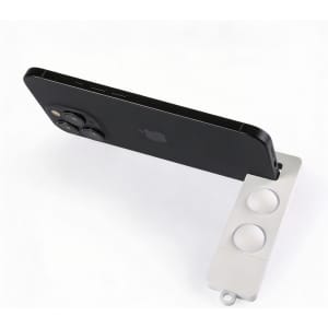 A white phone stand supports a black smartphone, featuring two circular grips for stability.