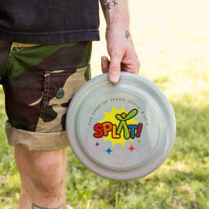 A grey frisbee is held in a person's hand, featuring a colourful logo and playful design.