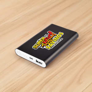 A black power bank with a logo and USB ports, resting on a wooden surface.