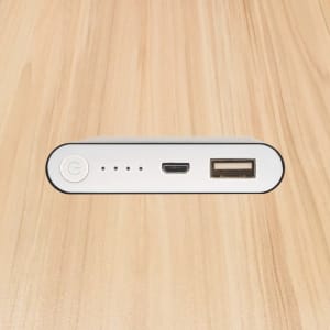A white power bank with a USB port, a micro USB port, and indicator lights, viewed from the top.