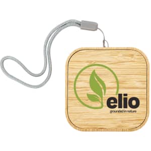 A square wireless charger in bamboo with a logo and a woven strap for easy carrying.