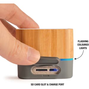A bamboo Bluetooth speaker featuring a grey base, an SD card slot, a charge port, and flashing coloured lights.