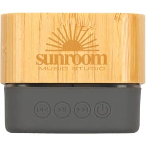 A bamboo Bluetooth speaker with a dark grey base, featuring buttons for playback and a branded logo.