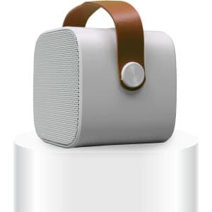 A compact grey boombox mini speaker with a brown handle and a button on the front, featuring a logo.