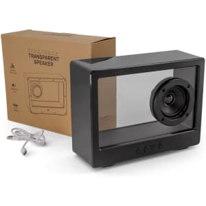 A black transparent speaker sits next to its box and a charging cable, showcasing a unique design with a visible speaker cone.