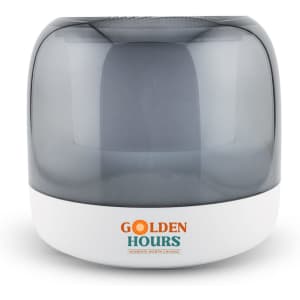 A compact grey and white speaker featuring a rounded design and a logo on the front.