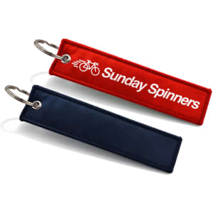 A red and a navy woven keytag with a metal keyring, featuring a logo on the red tag.