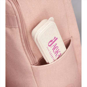 A bamboo fibre cutlery set in a beige case with a pink logo, tucked into a pink bag pocket.