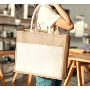A jute tote bag with a white pocket, featuring sturdy handles and a natural colour design.