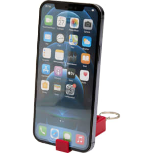 A red recycled plastic phone stand with an attached fidget toy, holding a smartphone displaying various apps.