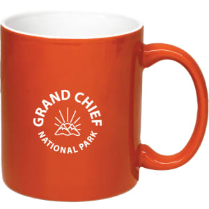 An orange coffee mug with a white interior and a logo featuring mountains and rays.