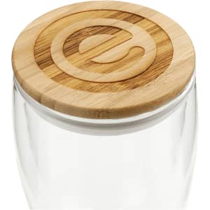A drink bottle with a clear glass body and a round bamboo lid, featuring a subtle branding element on top.
